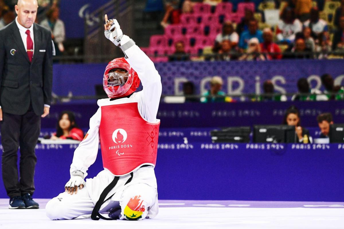 Para taekwondo fighter Idrissa Keita kneeling and pointing to the sky in celebration